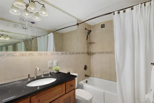 a bathroom with a granite countertop sink a mirror a bathtub and shower