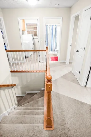 a view of staircase with railing and white walls