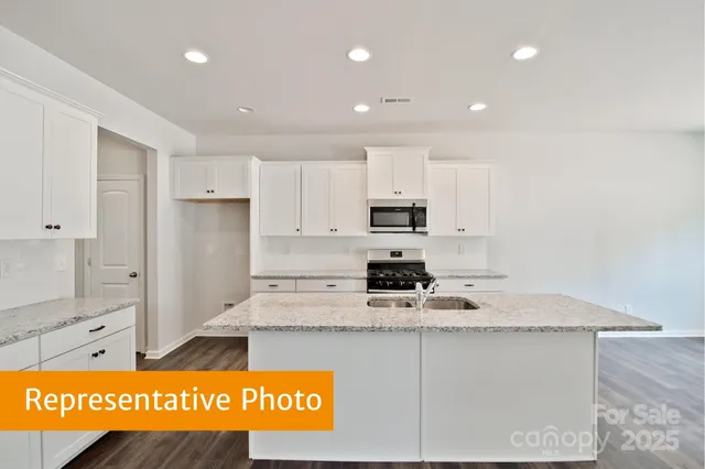 a kitchen with stainless steel appliances granite countertop a sink refrigerator and white cabinets