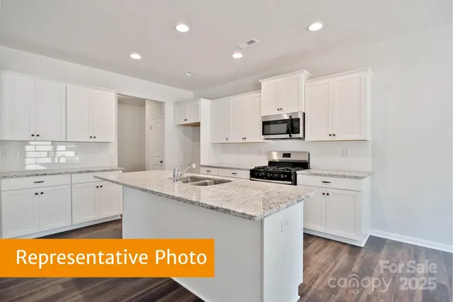 a kitchen with granite countertop a sink stainless steel appliances and white cabinets