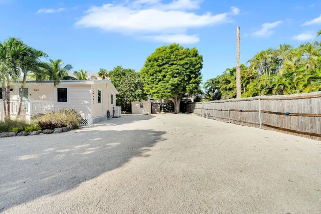 a view of a white house with a yard and plant in front of it