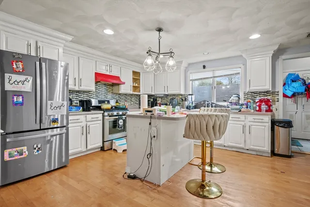 a kitchen with stainless steel appliances granite countertop a refrigerator a stove top oven a sink dishwasher and white cabinets with wooden floor