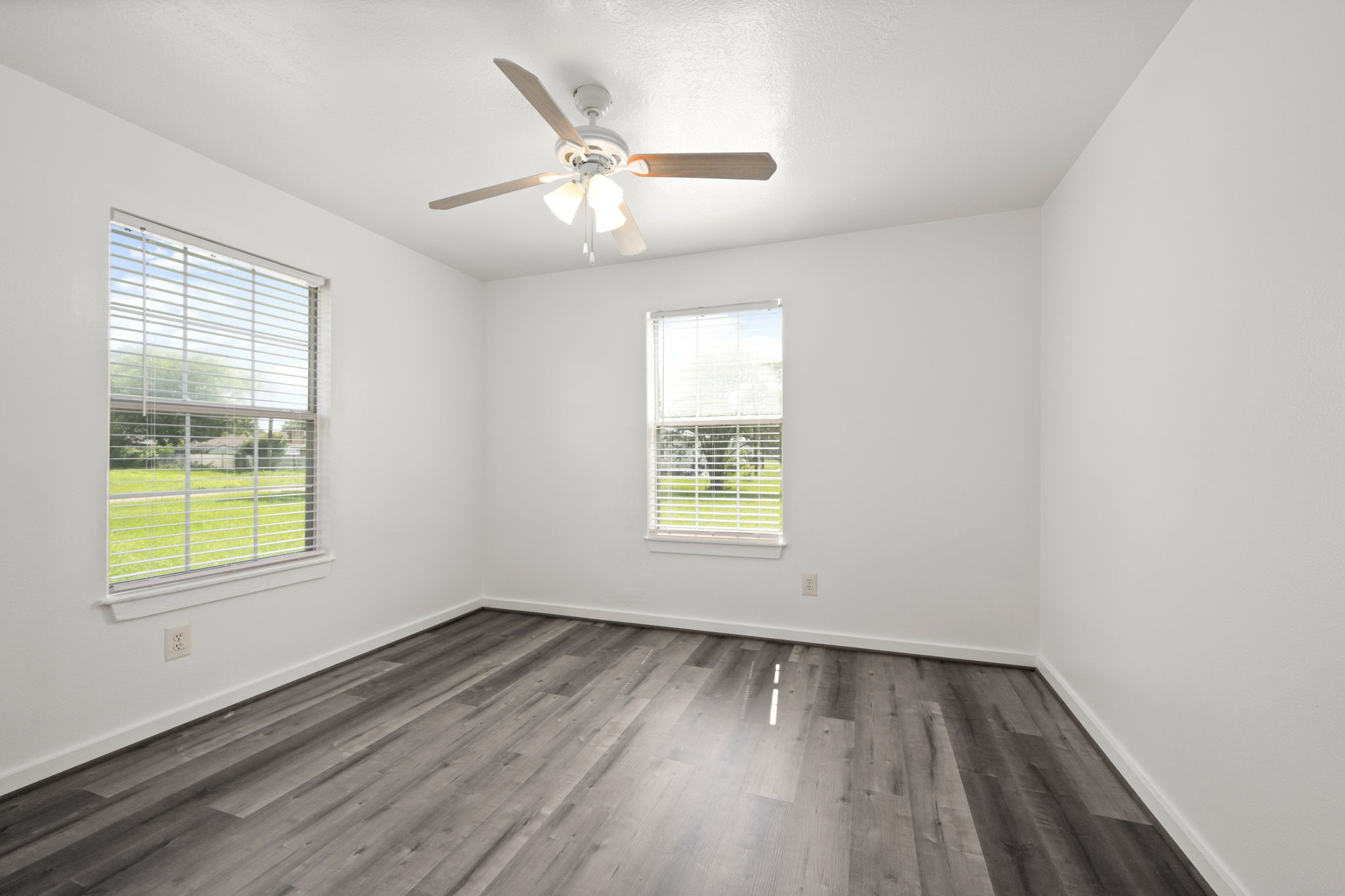 1935 1st Street Hempstead, TX 77445 - Photo 23 of 29 an empty room with wooden floor a ceiling fan and windows
