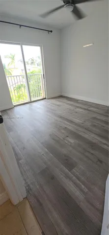 a view of an empty room with wooden floor and windows