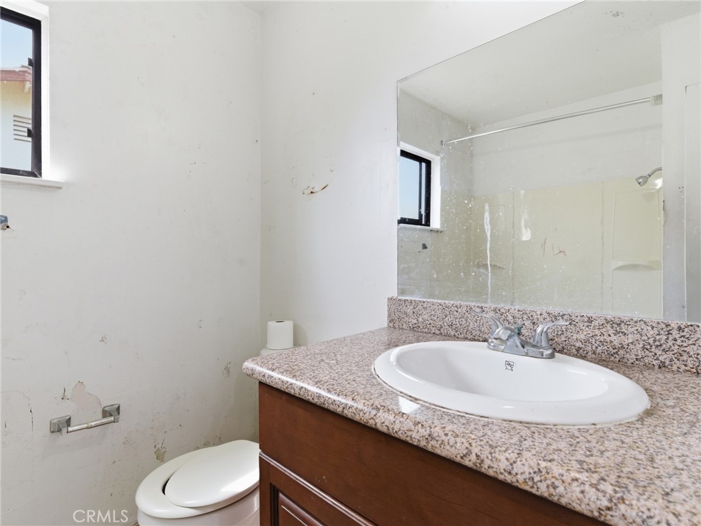 10127 Foothill Boulevard Sylmar, CA 91342 - Photo 11 of 33 a bathroom with a granite countertop sink a toilet and a mirror