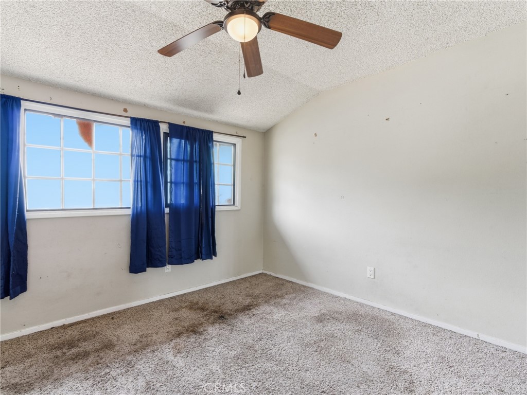 10127 Foothill Boulevard Sylmar, CA 91342 - Photo 25 of 33 an empty room with a ceiling fan and carpet