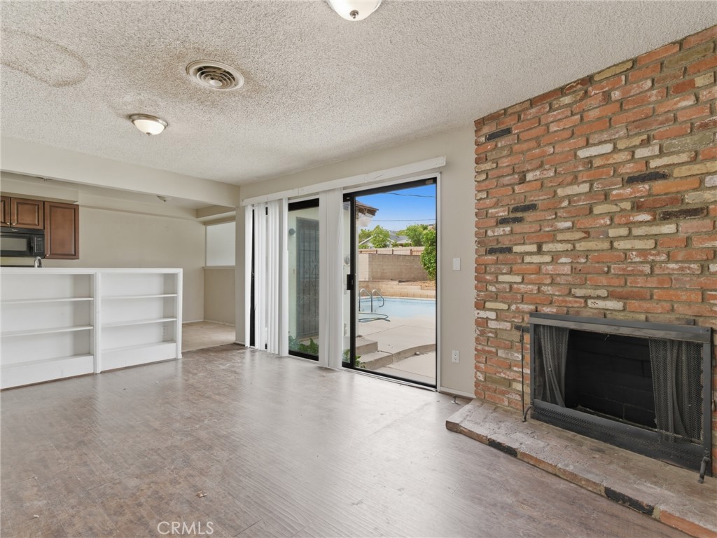10127 Foothill Boulevard Sylmar, CA 91342 - Photo 7 of 33 an empty room with wooden floor and fireplace