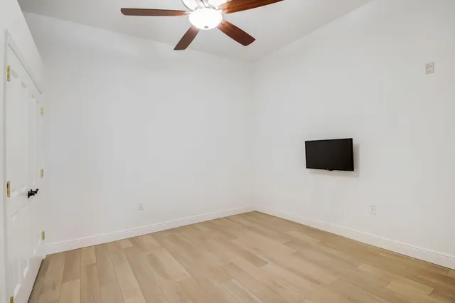 an empty room with a ceiling fan and windows