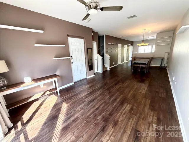 a view of a room with wooden floor ceiling fan and staircase