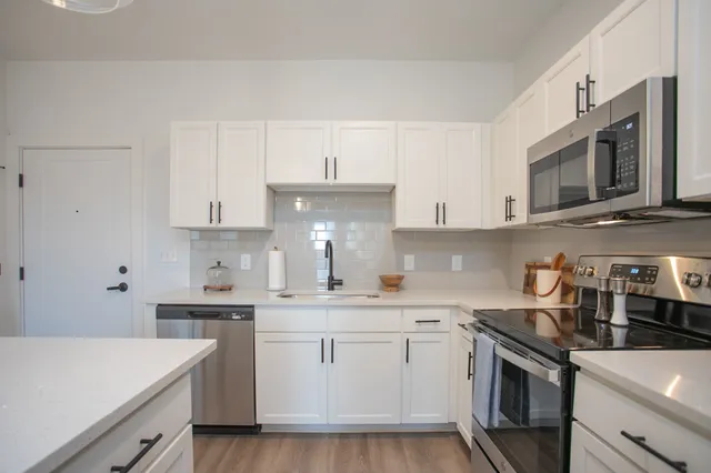 a kitchen with stainless steel appliances white cabinets sink and stove top oven