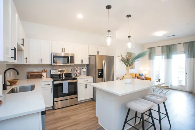 a large kitchen with stainless steel appliances kitchen island granite countertop a stove a sink dishwasher and a refrigerator with wooden floor