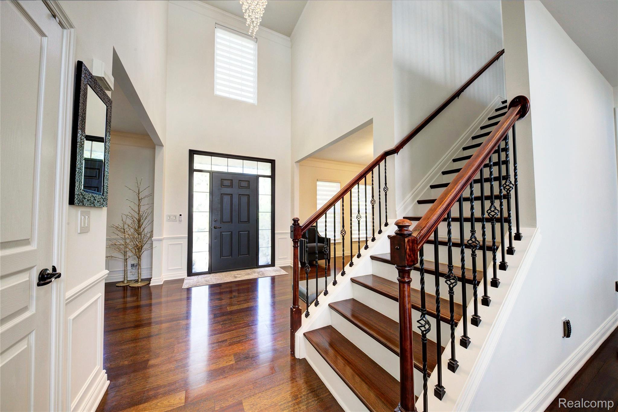 50411 Lansdowne Road Canton, MI 48188 - Photo 5 of 75 Two-story foyer featuring wood-finish flooring, a dark wood staircase with wrought iron balusters, wainscoting, and a prominent dark paneled entry door with sidelights and transom window