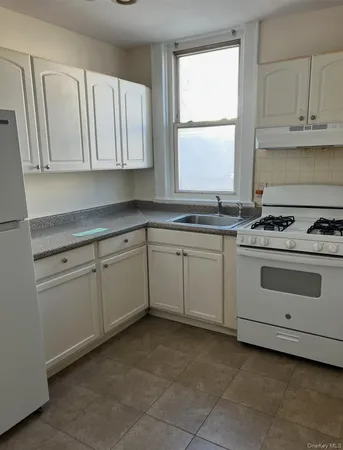 a white kitchen with granite top and stainless steel appliances