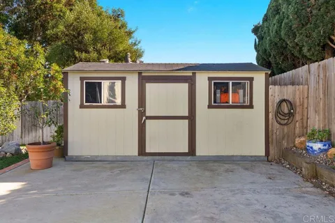 a view of a backyard with white wall and wooden fence