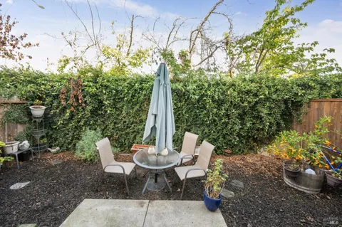 a view of a patio with table and chairs potted plants and wooden fence