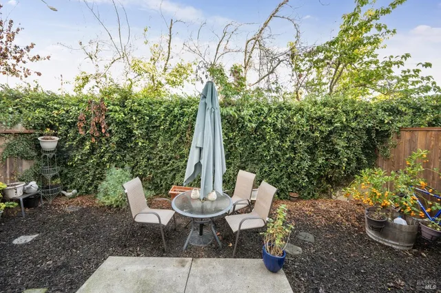 a view of a patio with table and chairs potted plants and wooden fence