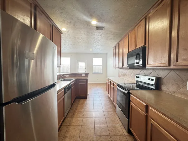 a kitchen with stainless steel appliances granite countertop a refrigerator a stove top oven a sink and dishwasher