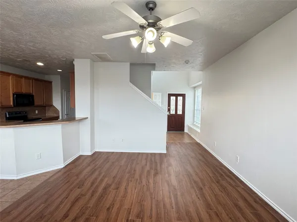 a view of empty room with wooden floor and ceiling fan