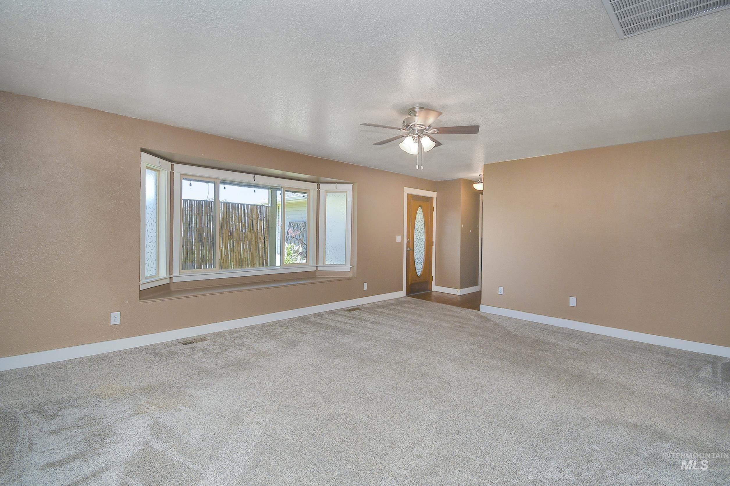 1108 East Ustick Road Caldwell, ID 83607 - Photo 14 of 30 Expansive living area featuring a neutral carpet flooring, light tan wall finish, and a ceiling fan with integrated lighting