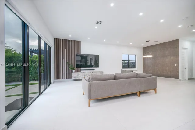 a living room with furniture flat screen tv and a floor to ceiling window