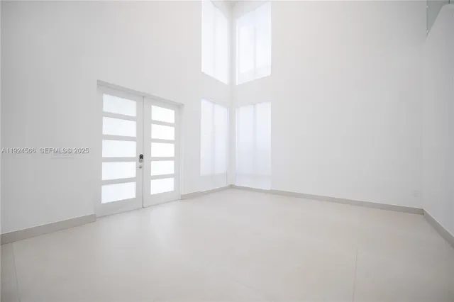 an empty room with windows and chandelier fan