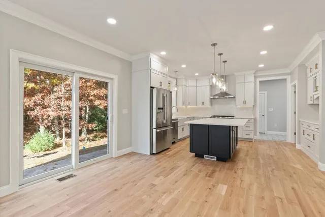 a large kitchen with stainless steel appliances kitchen island a large counter top and wooden floors