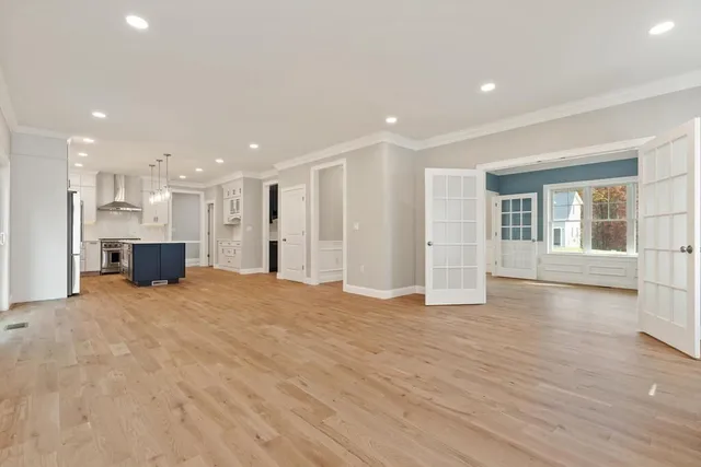 a view of an empty room with kitchen and window