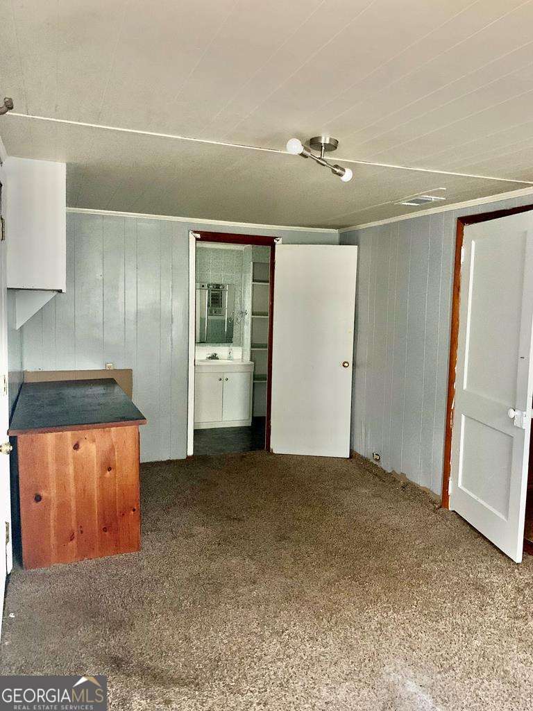 606 West 7th Street Alma, GA 31510 - Photo 18 of 28 an empty room with wooden floor and cabinet