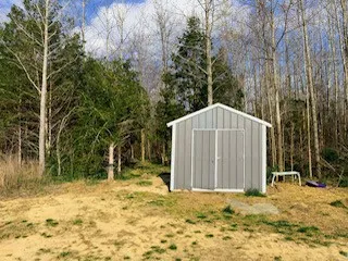 a view of a wooden house with large trees and covered area
