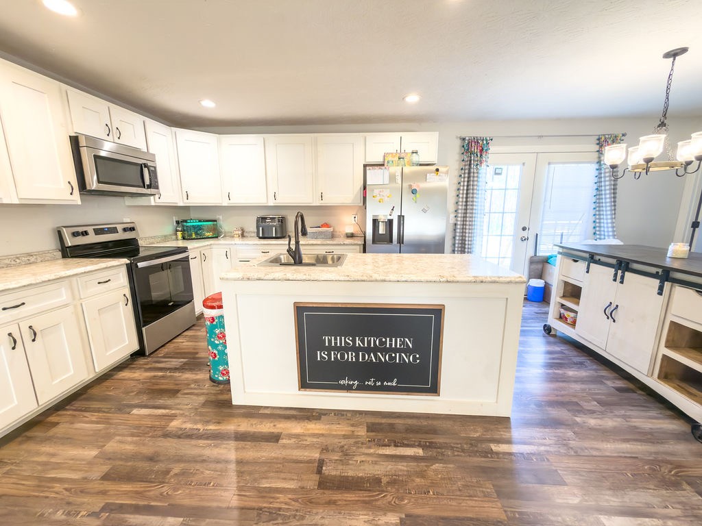 392 Scott Road Sharon Grove, KY 42280 - Photo 9 of 36 a kitchen with stainless steel appliances granite countertop a stove top oven a sink a refrigerator white cabinets and wooden floor