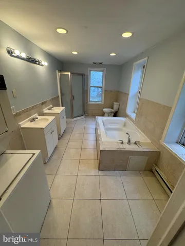 a large bathroom with a tub and view of living room