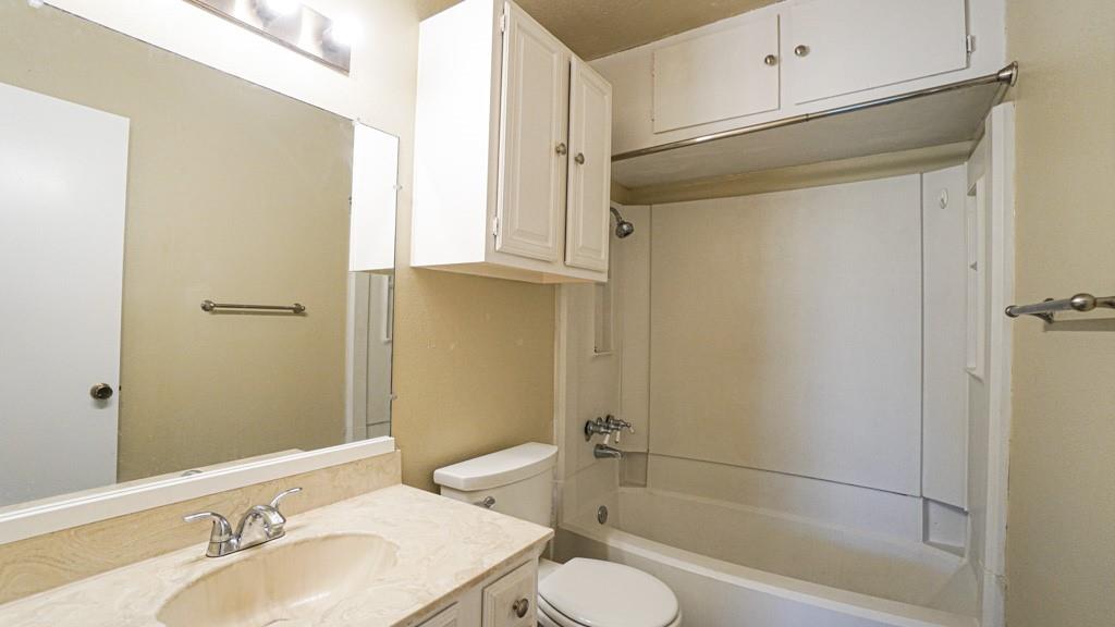 2505 Wedglea Drive, Unit 121 Dallas, TX 75211 - Photo 14 of 24 a bathroom with a granite countertop sink toilet and shower