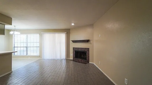 an empty room with wooden floor fireplace and windows