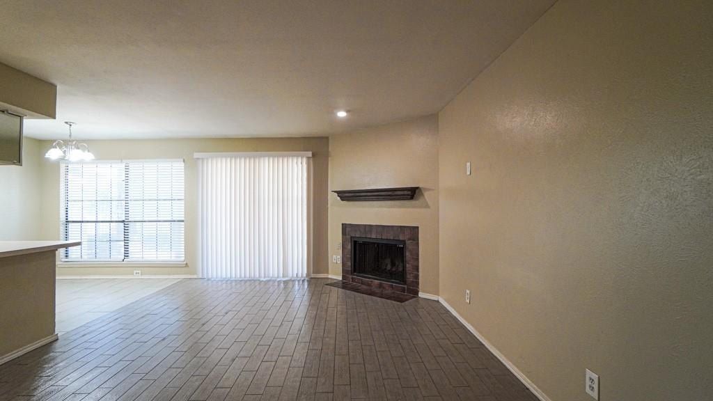 2505 Wedglea Drive, Unit 121 Dallas, TX 75211 - Photo 5 of 24 an empty room with wooden floor fireplace and windows