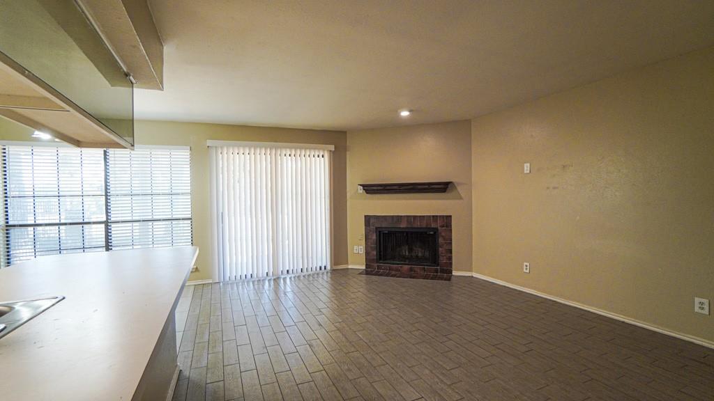 2505 Wedglea Drive, Unit 121 Dallas, TX 75211 - Photo 7 of 24 an empty room with wooden floor fireplace and windows