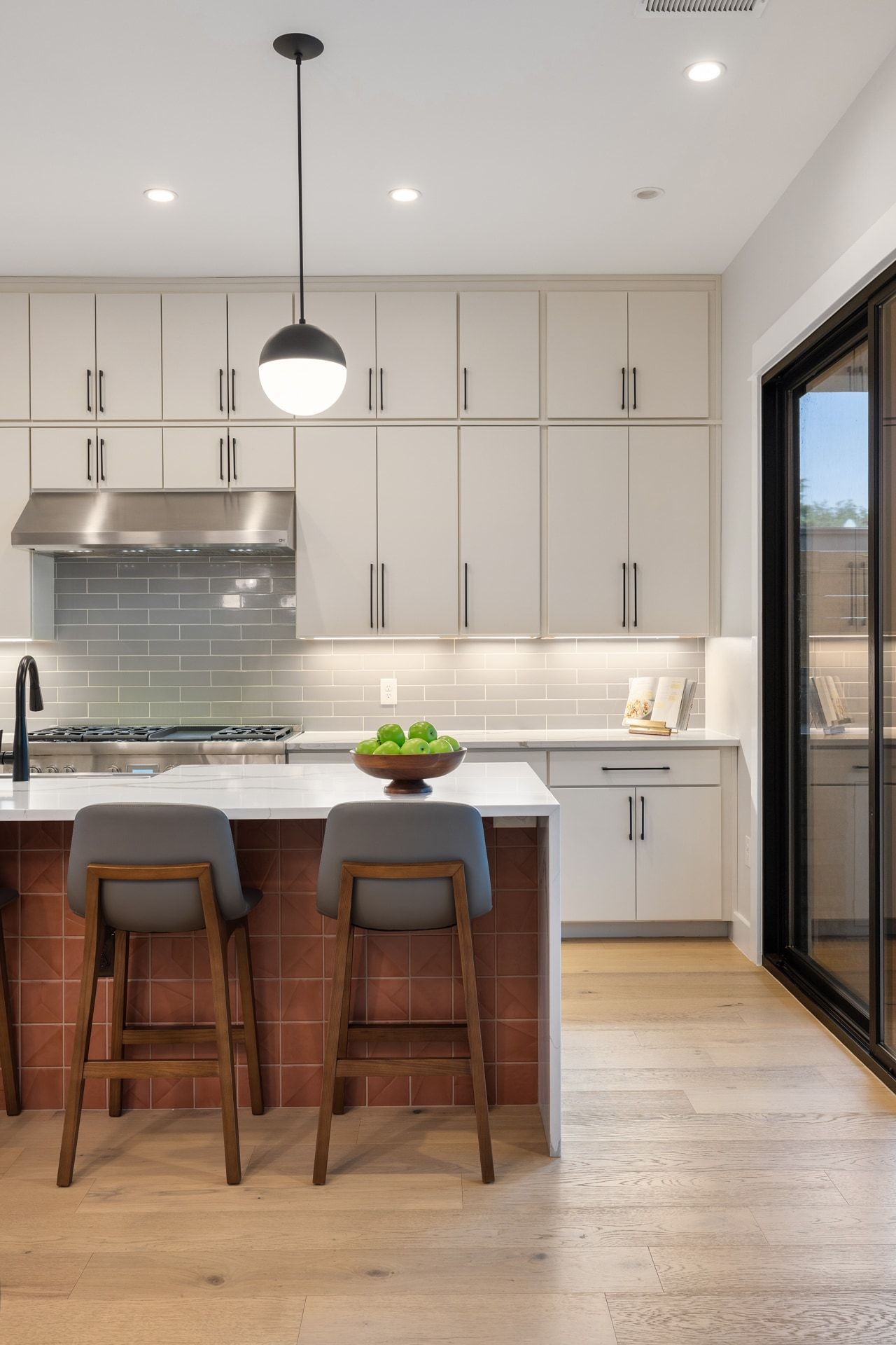 5405 Montview Street Austin, TX 78756 - Photo 5 of 40 A contemporary kitchen features sleek white cabinetry, an island with a breakfast bar, and light hardwood floors.