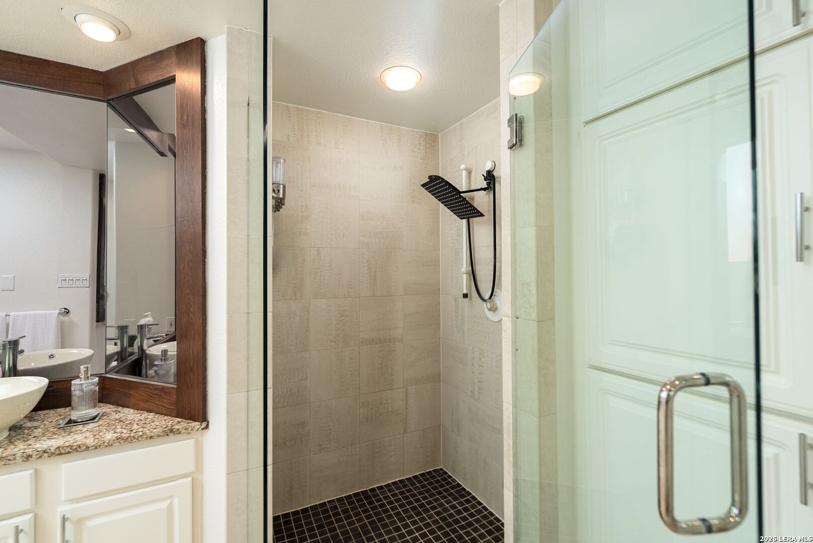 7701 Wurzbach Road, Unit 2302 San Antonio, TX 78229 - Photo 18 of 49 a bathroom with a granite countertop sink a mirror and shower