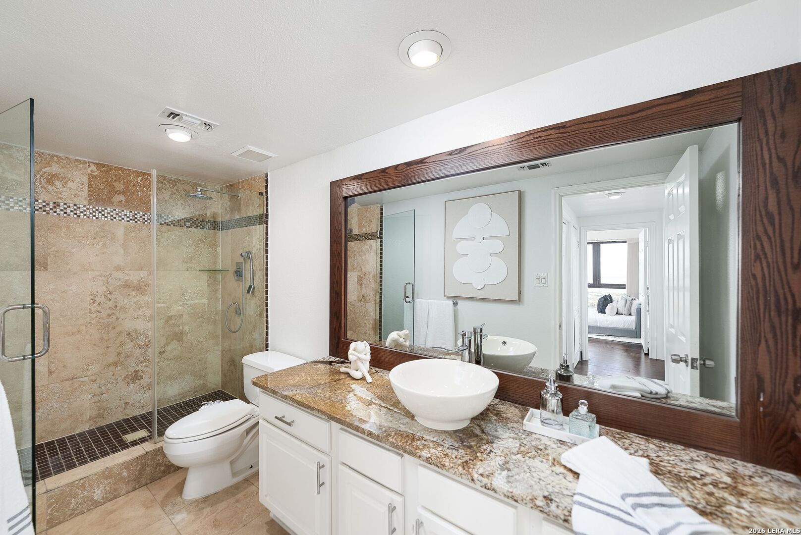 7701 Wurzbach Road, Unit 2302 San Antonio, TX 78229 - Photo 25 of 49 a bathroom with a granite countertop sink toilet a mirror and shower