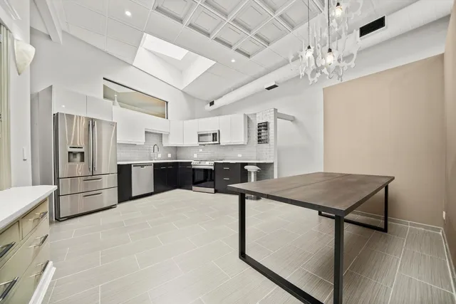 a kitchen with stainless steel appliances kitchen island a table chairs refrigerator and microwave