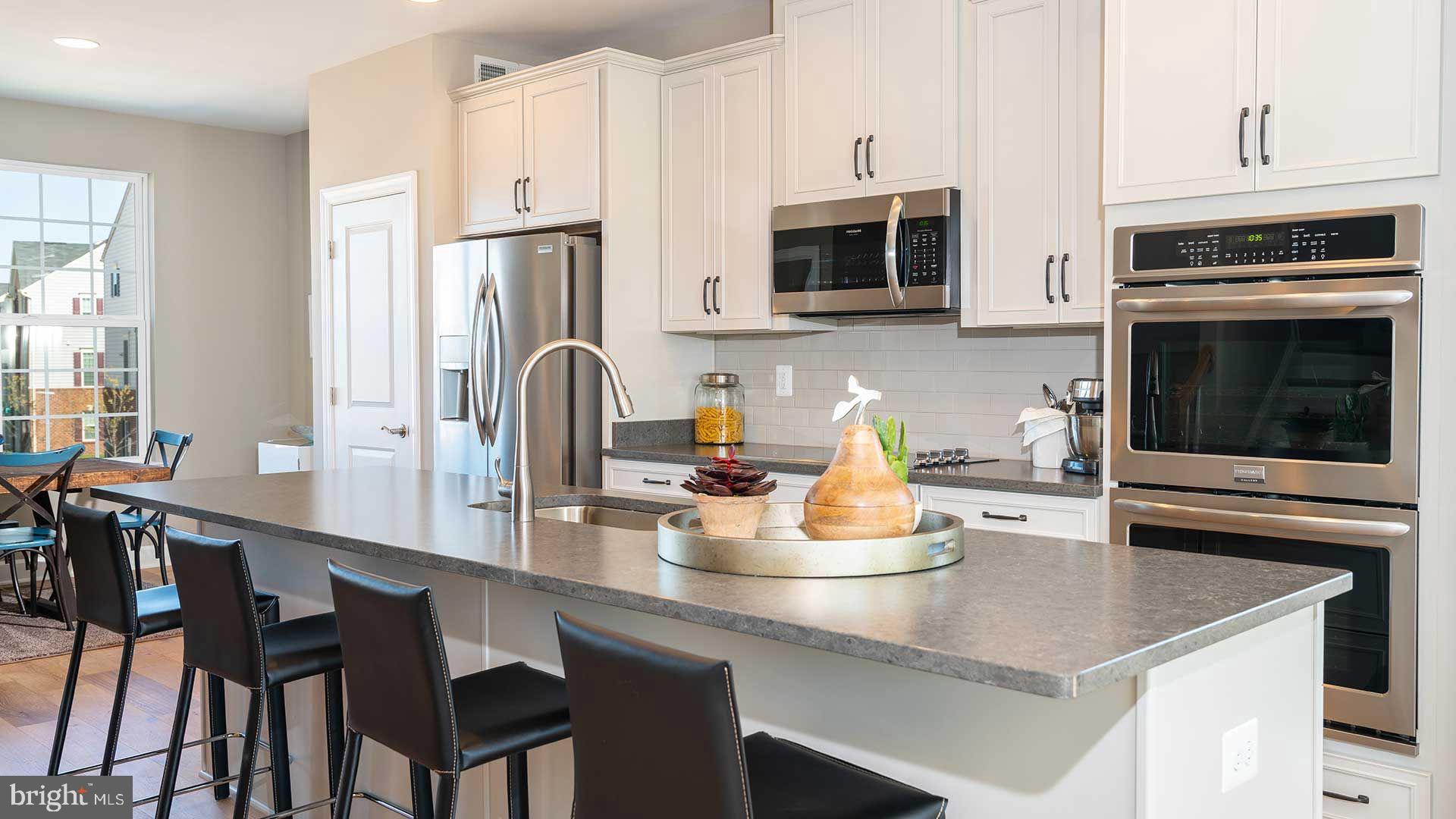 316 Anthem Street Ranson, WV 25438 - Photo 5 of 33 a kitchen with stainless steel appliances a table chairs microwave and cabinets