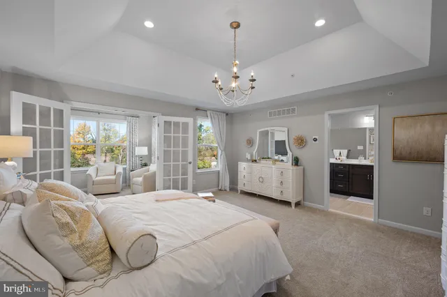 a spacious bedroom with a large bed a chandelier and windows
