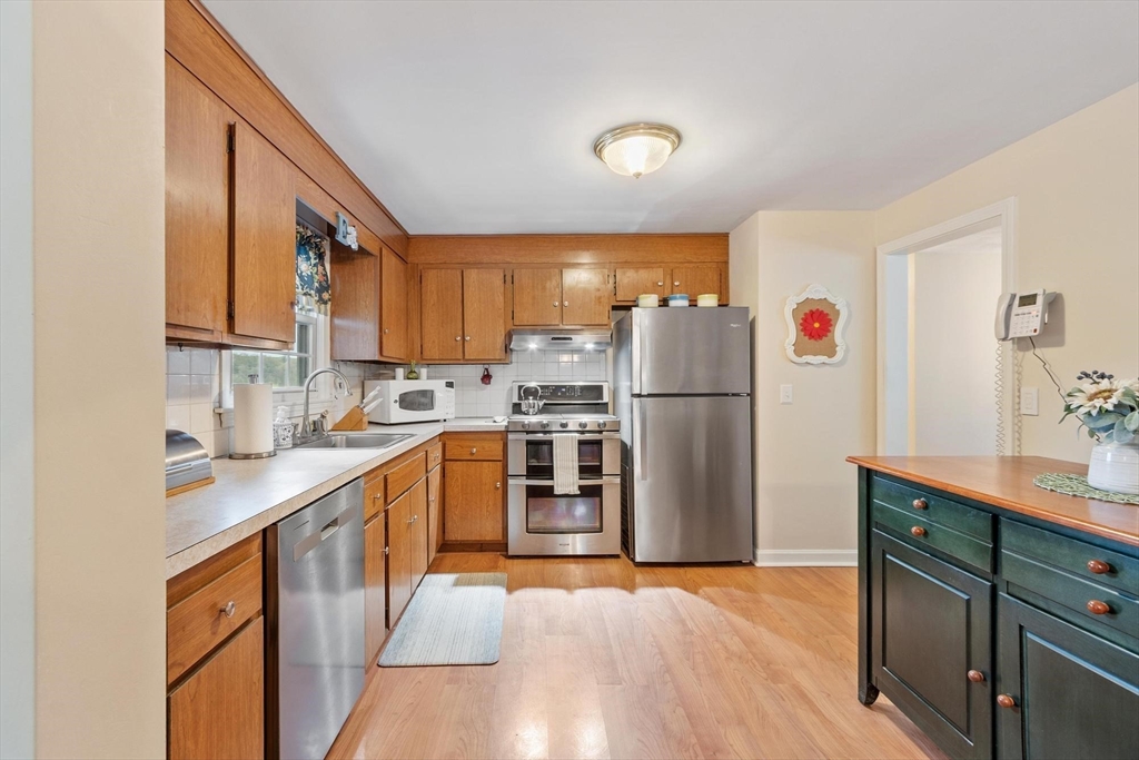 134 River Road Lowell, MA 01852 - Photo 11 of 36 a kitchen with stainless steel appliances granite countertop a refrigerator a sink dishwasher a stove with wooden cabinets and floors