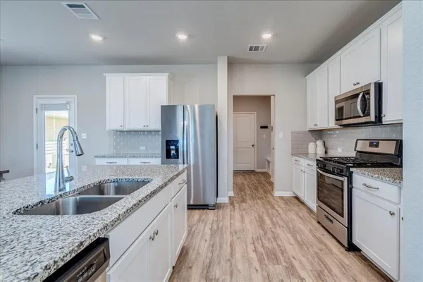 a kitchen with stainless steel appliances granite countertop a refrigerator a stove a sink and a microwave