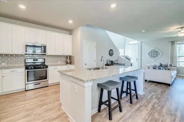 a kitchen with stainless steel appliances kitchen island granite countertop a kitchen island hardwood floor sink and stove