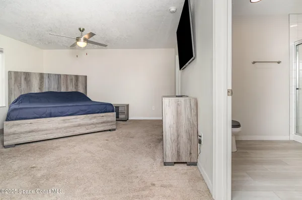 a spacious bedroom with a bed and a flat tv screen