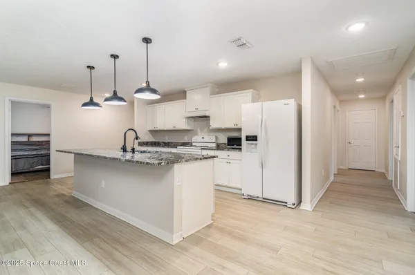 a kitchen with stainless steel appliances granite countertop a sink a stove a refrigerator and island with wooden floor