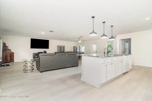 a kitchen with stainless steel appliances granite countertop a sink a stove a refrigerator and a wooden floor