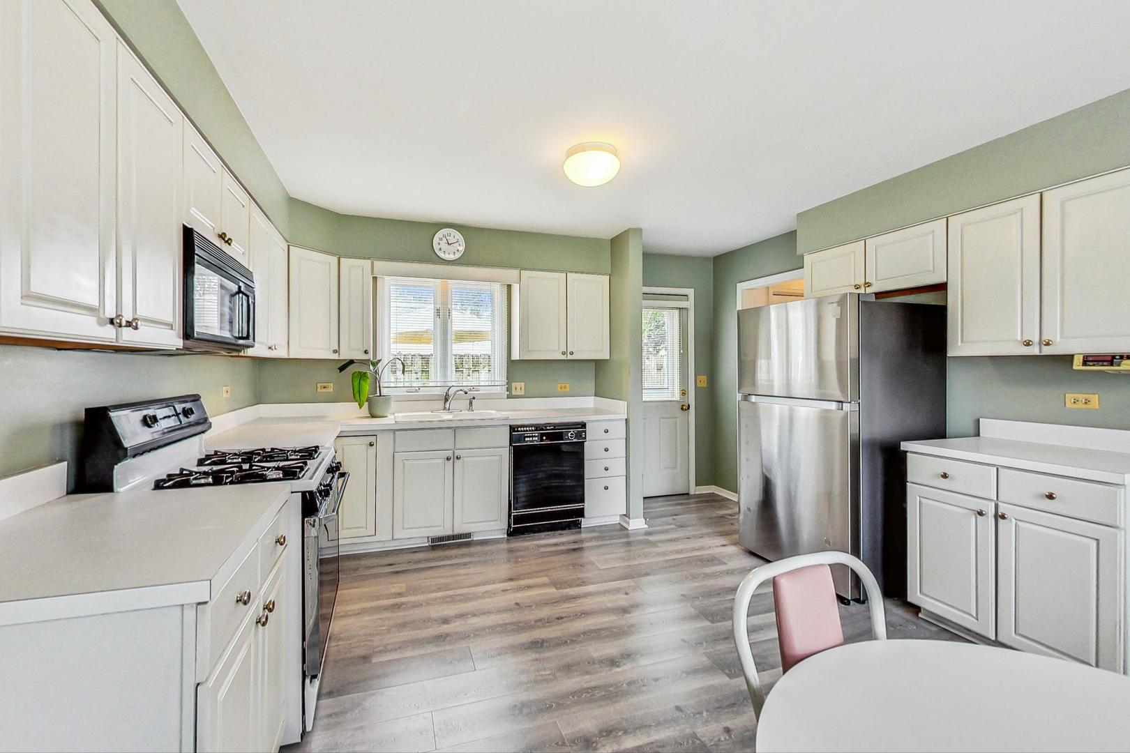 1010 Aurora Way Wheaton, IL 60189 - Photo 8 of 37 a kitchen with stainless steel appliances a stove a sink a refrigerator white cabinets and wooden floor