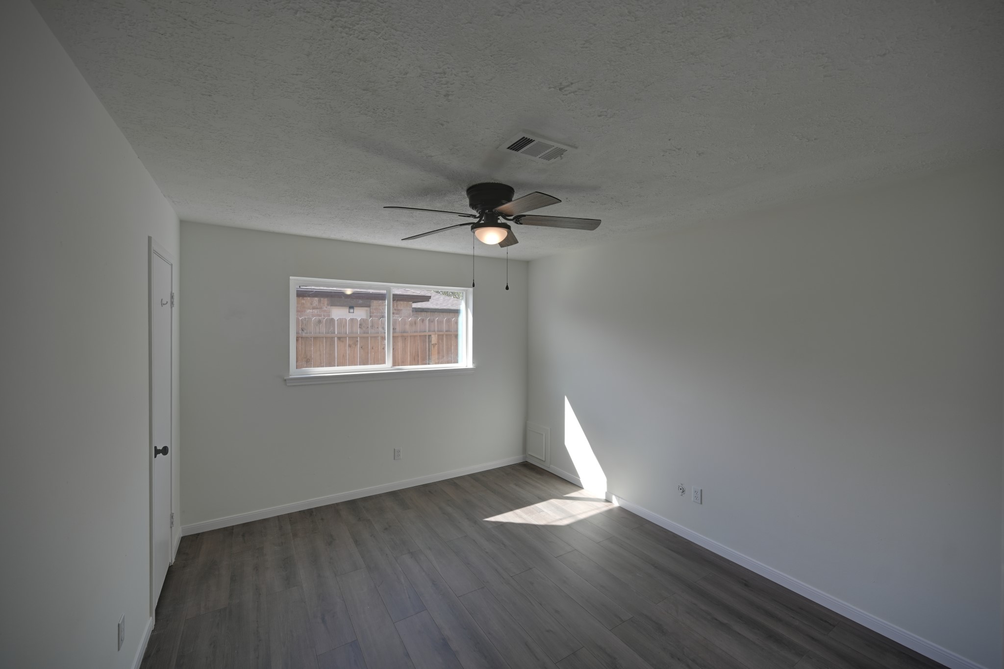 10410 Cook Road Houston, TX 77099 - Photo 9 of 12 an empty room with wooden floor chandelier fan and windows