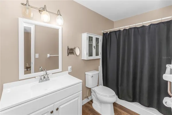 a bathroom with a sink a toilet a mirror and shower curtain
